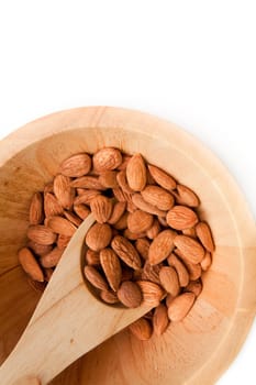 Wooden spoon with almonds in a bowl against a white background