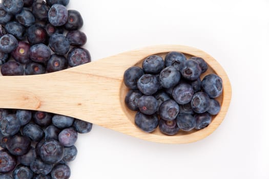 Wooden spoon with blueberry against a white background