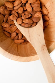 Wooden spoon traditional with almonds in a bowl against a white background