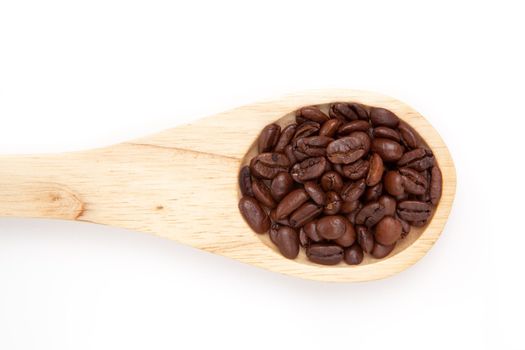 Wooden spoon with coffee seeds  against a white background
