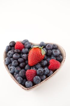 Fruits  in a heart shaped bowl against a white background