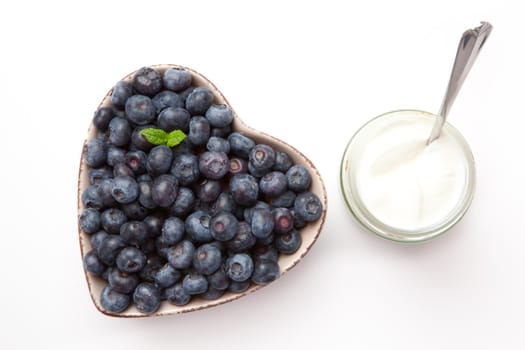 White yogurt and blueberries in a bowl  against a white background