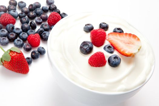 Bowl of cream with berries against a white background