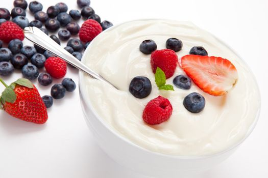 Bowl of cream with  different berries against a white background