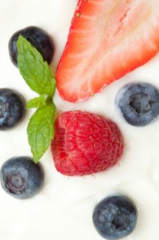 Different berries in cream against a white background