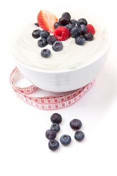 Berries cream in a bowl with a tape measure against a white background