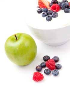 Apple and bowl of berries cream against a white background
