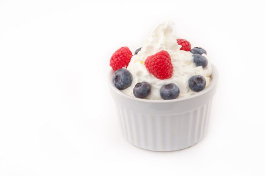Jar of berries and whipped cream against white background