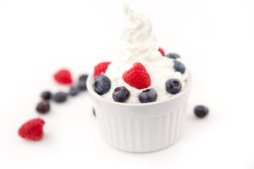 Dessert of berries and whipped cream against white background