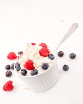 Whipped cream mix with berries and spoon against white background