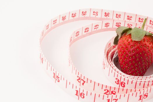 Close up of a strawberry surrounded by a ruler against a white background
