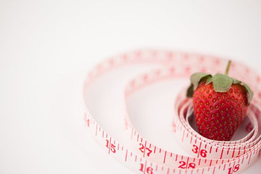 Strawberry surrounded by a ruler against a white background