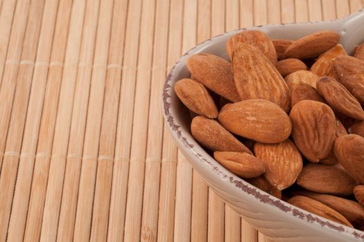 Roasted almonds in bowl on a bamboo placemat