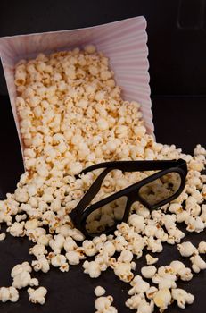 3D glasses on falling pop corn out of a box against a black background