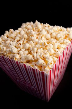Close up of a box full of pop corn against a black background