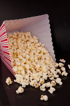 Pop corn falling out of a box against a black background