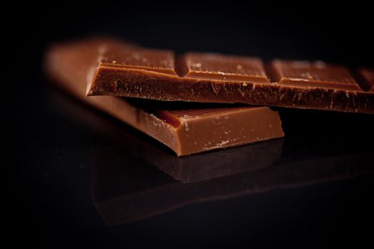 Two blurred bar of dark chocolate against a black background
