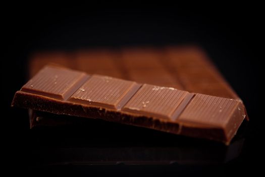 Blurred bar of dark chocolate against a black background