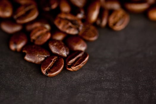 Many dark blurred coffee seeds laid out together on a black table