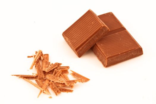 Chocolate pieces and chocolate shavings against a white background