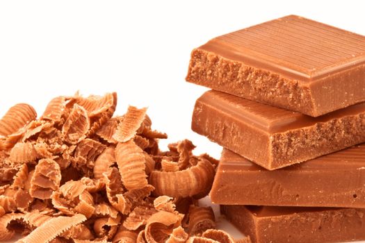 Pile of chocolate pieces and chocolate shavings against a white background