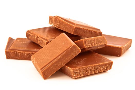 Many pieces of milk chocolate against a white background