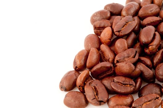 Many dark blurred coffee seeds laid out together against a white background