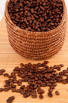 Close up of a basket filled with coffee seeds on a wooden tablecloth against a white background