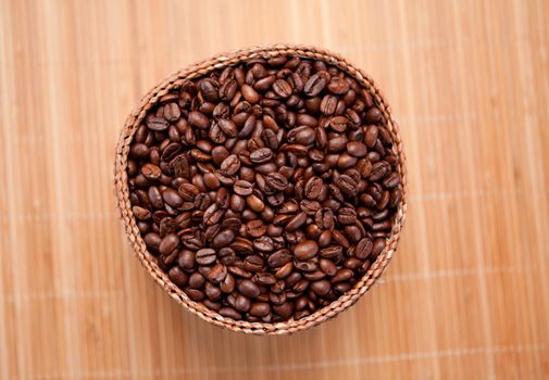 Many roasted coffee seeds in a wooden basket