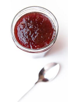 Jar of jam  and spoon against a white background