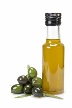 Glass bottle of premium virgin olive oil and some olives with leaves isolated on a white background