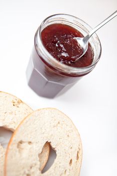 Jam with slice of bagel against a white background
