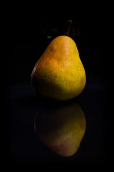 One fresh Pear on black background with reflection