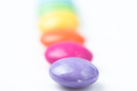 Line of candies multi coloured against a white background