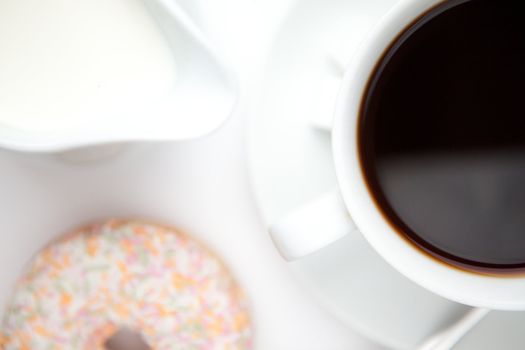 Cup of coffee with a doughnut against a white background