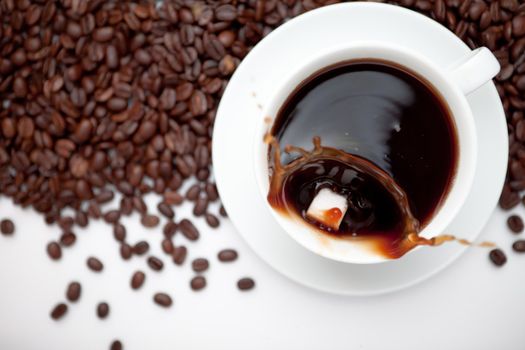 Cup of coffee with beans against a white background
