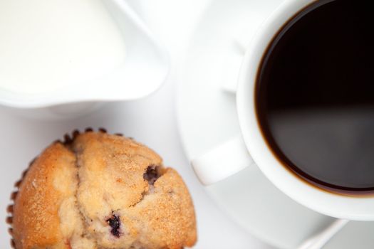 Cup of coffee with muffin against a white background