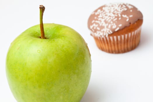 Apple and cupcake against a white background