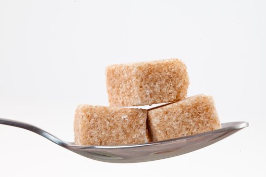 Spoon with  brown sugar against white background