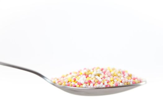 Sprinkles in a spoon against white background