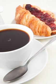Coffee cup with croissant against white background