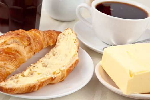 Breakfast with a croissant spread with butter indoors