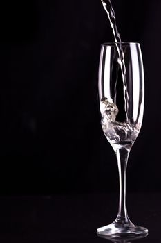 Empty champagne flute being filled against black background