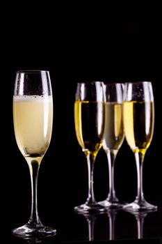 Four full flutes of champagne against black background