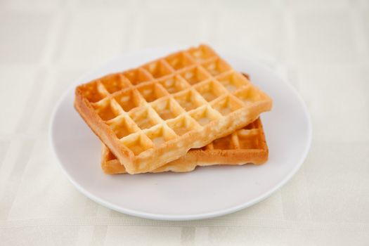 Two waffles on a saucer on a table