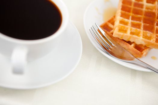 Waffles placed next to a coffee cup on a table