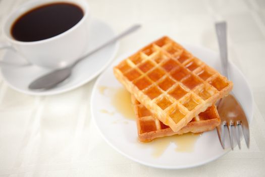 Waffles placed near a coffee cup on a table