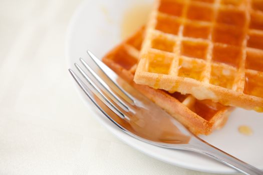 Two waffles and a fork on a saucer on a table