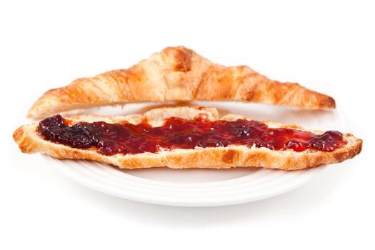 Croissant spread with jam in a plateful against white background