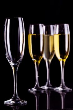 Three full glasses of champagne and one empty against black background